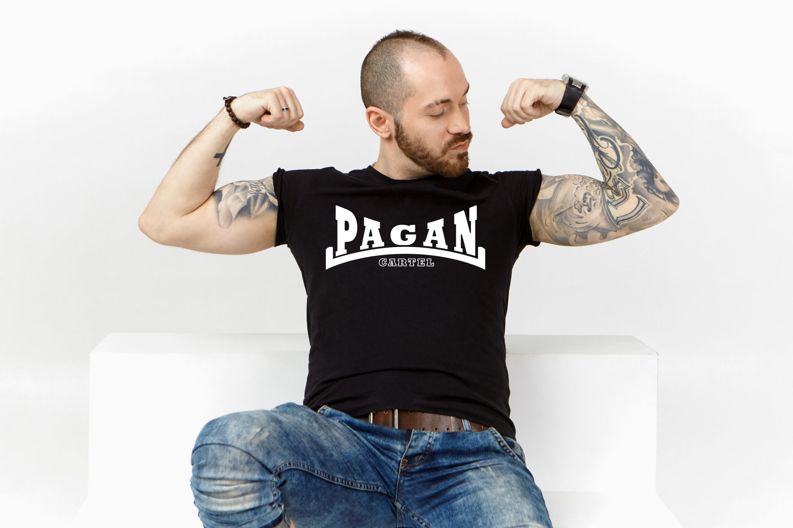 Strong male bodybuilder with stubble, stylish hairdo and tattooed arms, demonstrating his biceps, tensing muscles after weightlifting exercise, feeling proud of himself, posing isolated in studio